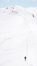 Rear view of man walking snow covered mountain