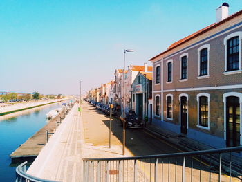 Canal amidst buildings against clear blue sky