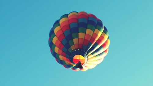 Low angle view of colorful hot air balloon flying against clear blue sky