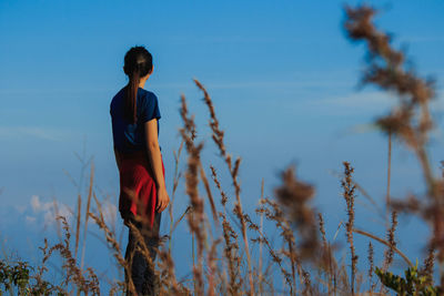 Rear view of woman standing on field against sky