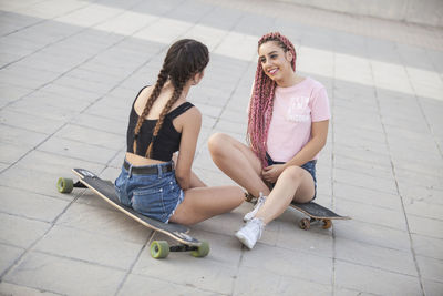 High angle view of friends sitting on skateboard