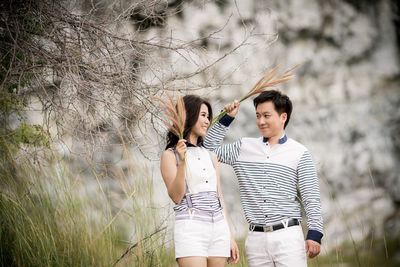 Young couple standing against trees