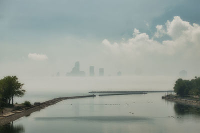 Scenic view of lake by buildings against sky