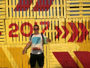 Portrait of smiling man standing against yellow wall