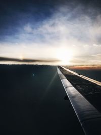 Airplane flying over sea against sky during sunset