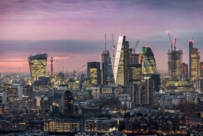 Illuminated buildings in city at sunset