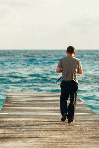 Rear view of man on beach against sky