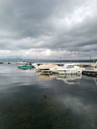 Boats moored in marina against cloudy sky