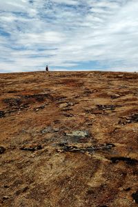 Man walking on landscape against sky