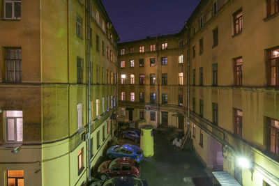 Illuminated street amidst buildings in city at night