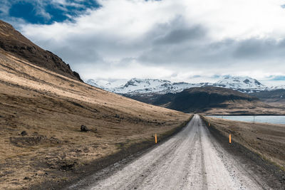 Road amidst mountains against sky during winter