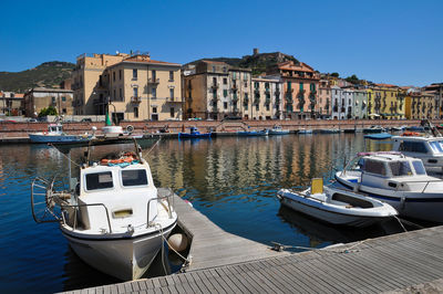 Sailboats moored on canal by buildings in city against clear sky