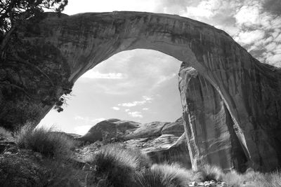 Low angle view of arch bridge on rock formation against sky