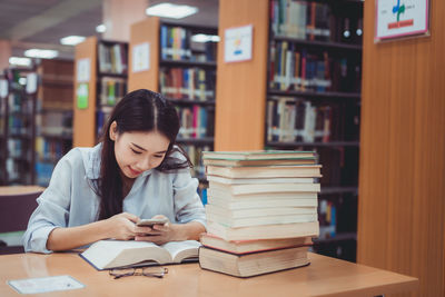 Woman using mobile phone while sitting at library