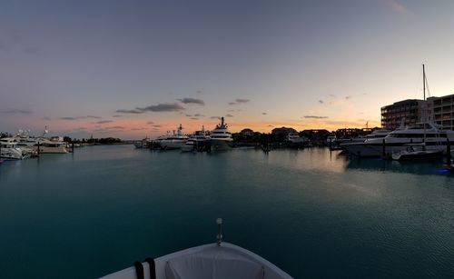 Boats in river against sky during sunset