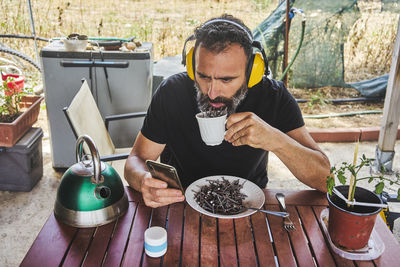 Midsection of man holding a cup full of nails pretending to drink it