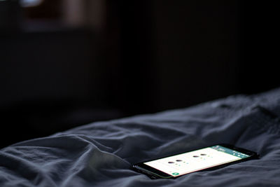 Close-up of mobile phone on bed at home