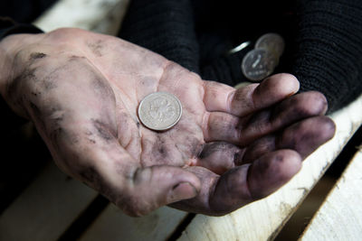 High angle view of messy hands over coins in hat on table