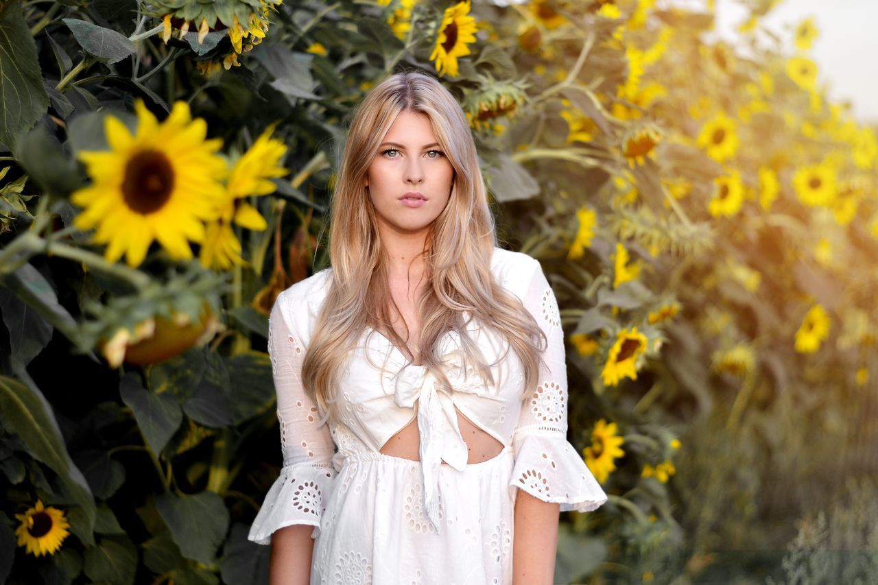 one person, leisure activity, young adult, beautiful woman, hair, young women, front view, long hair, standing, plant, beauty, real people, lifestyles, portrait, hairstyle, flower, flowering plant, blond hair, women, yellow, outdoors