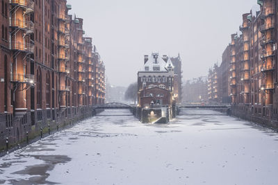 Road amidst buildings in city during winter