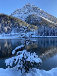 Frozen lake by snowcapped mountain against sky