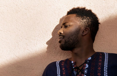 Portrait of young man looking away against wall