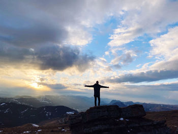 Man standing on rock against sky