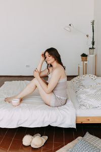 Young woman sitting on bed at home