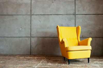 Empty yellow chair against gray wall