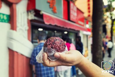 Close-up of man holding ice cream in city