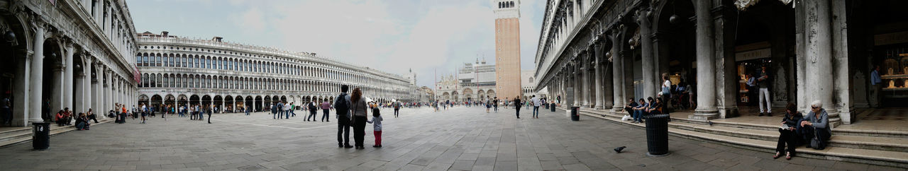 Panoramic shot of people walking by built structures