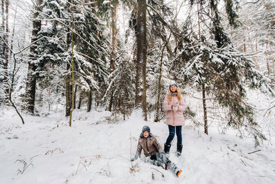 Happy boy with a girl sitting in the snow in the forest