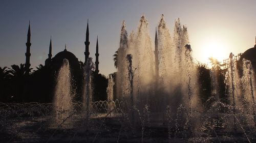 Fountain at silhouette sultan ahmed mosque against clear sky during sunset