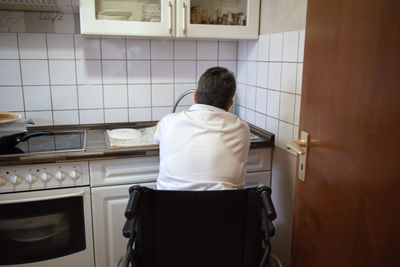 Rear view of woman standing in kitchen