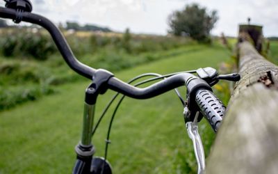 Cropped image of bicycle handle by wooden fence