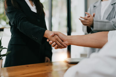 Midsection of business people shaking hands