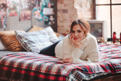 Portrait of smiling young woman relaxing on bed