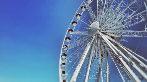 Low angle view of ferris wheel against clear blue sky