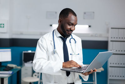 Doctor using laptop while standing in office