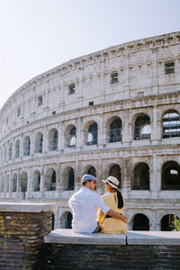 Rear view of couple embracing against amphitheater