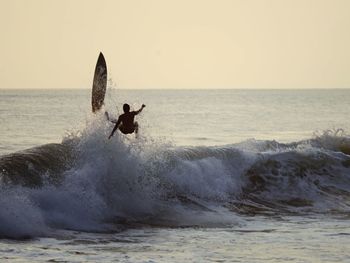 Man jumping on sea against clear sky