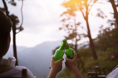 Camping concept, cheers glass bottle by camping people together at their camping site