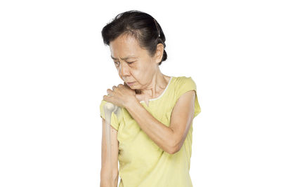 Woman looking away while standing against white background