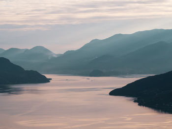 Scenic view of sea and mountains against sky at sunset