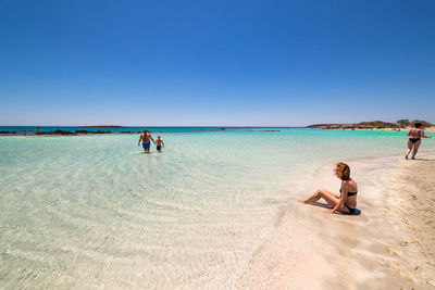 Woman on beach against clear blue sky