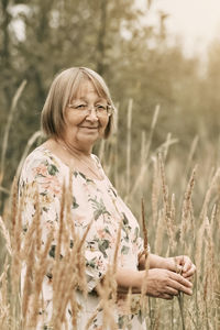 An elderly woman in the tall grass with spikelets. autumn.
