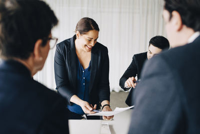 Businesswoman smiling while explaining ideas to colleagues in board room at office