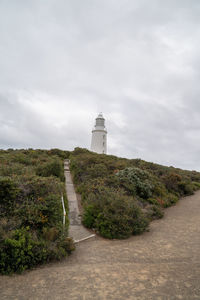 Lighthouse amidst plants and buildings against sky