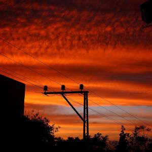 Silhouette of power lines against cloudy sky