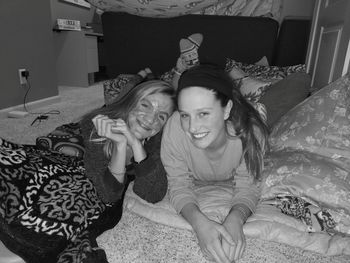 Portrait of smiling young woman sitting on bed at home